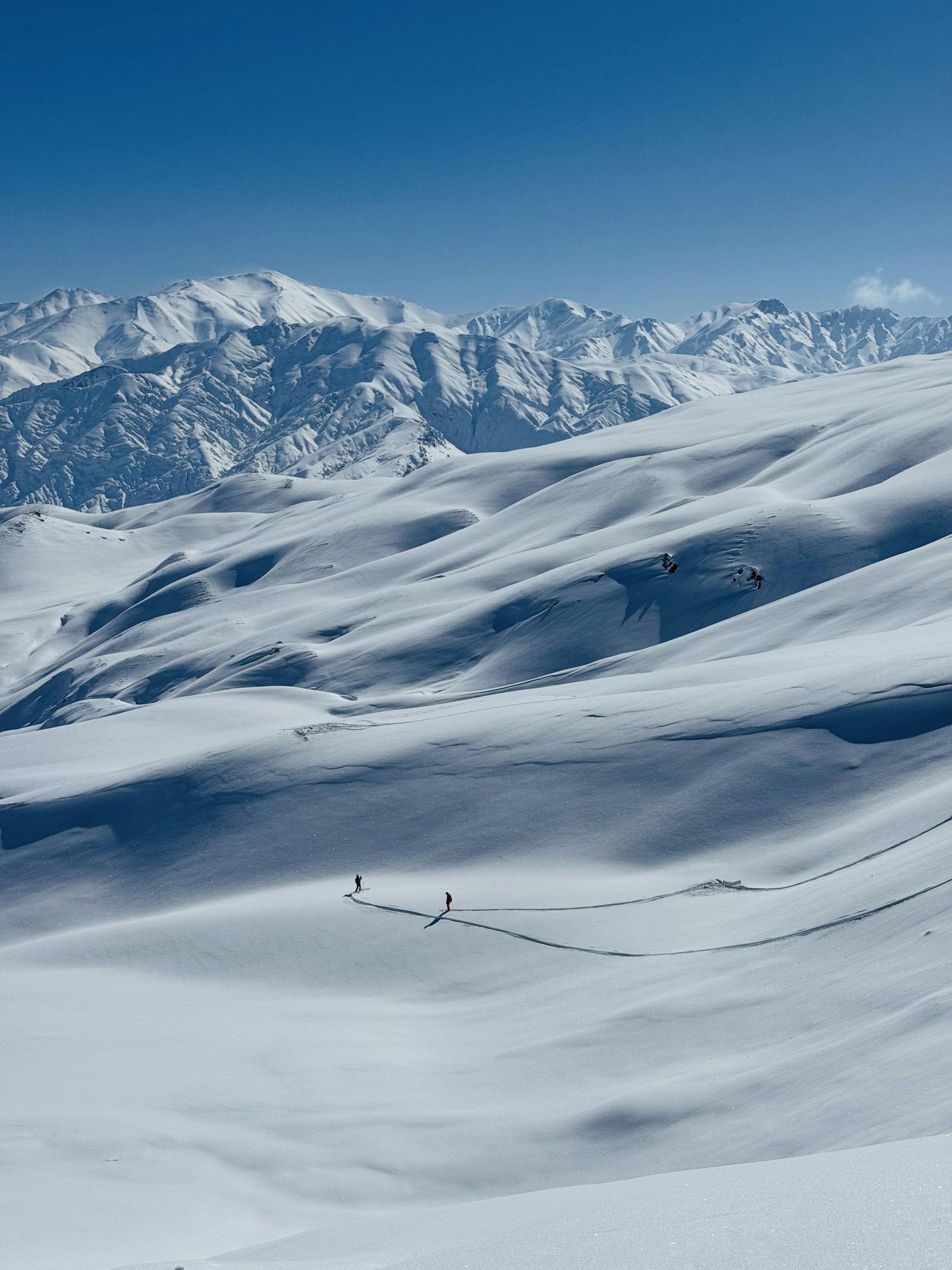 Two skiers sharing a quiet moment in an immense snowy mountain landscape
